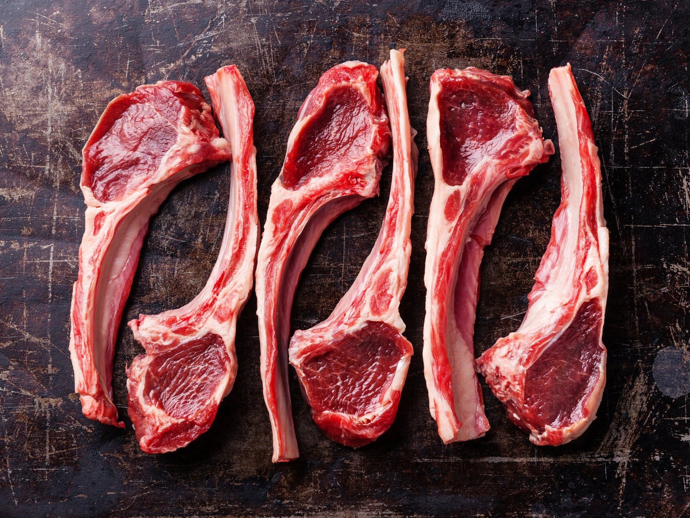 Fresh, uncooked beef rib chops arranged on a rustic wooden surface, showcasing rich red meat and marbling, ideal for grilling or roasting.